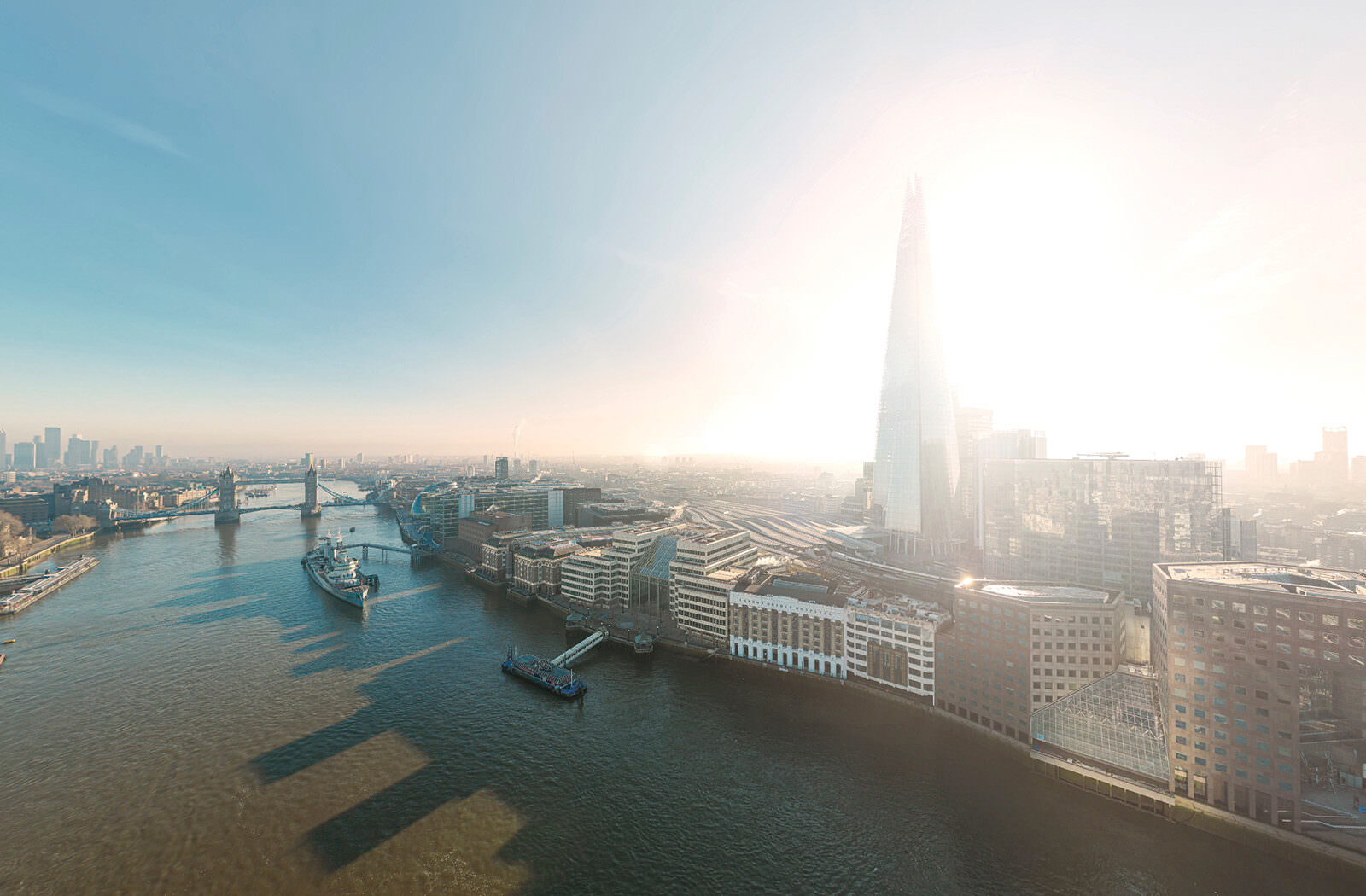 Aerial view from the Thames over the City of London with the sun shining directly behind The Shard