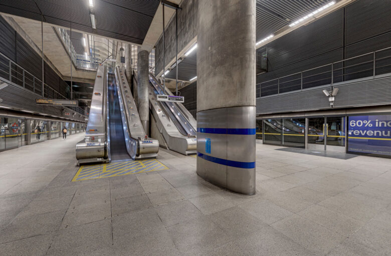 Virtual recce - a futuristic view at the base of escalators at Canary Wharf with large, elliptical column in the foreground.