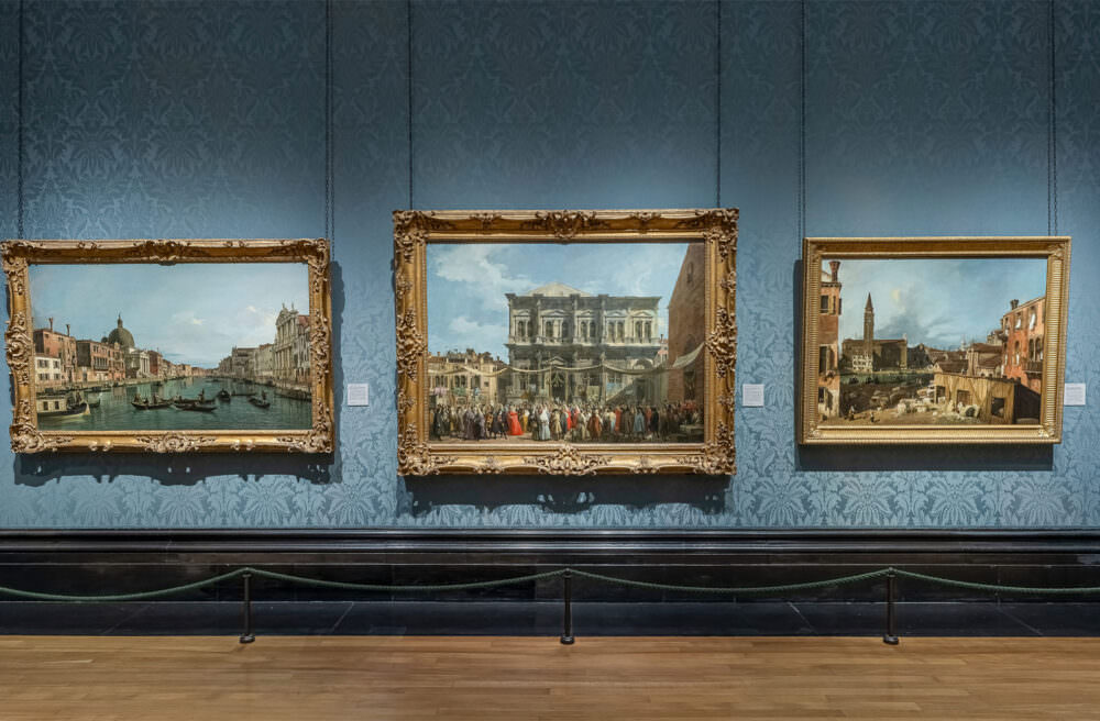 Still taken from the National gallery virtual tour showing 3 gilt-framed artworks against a blue wall.